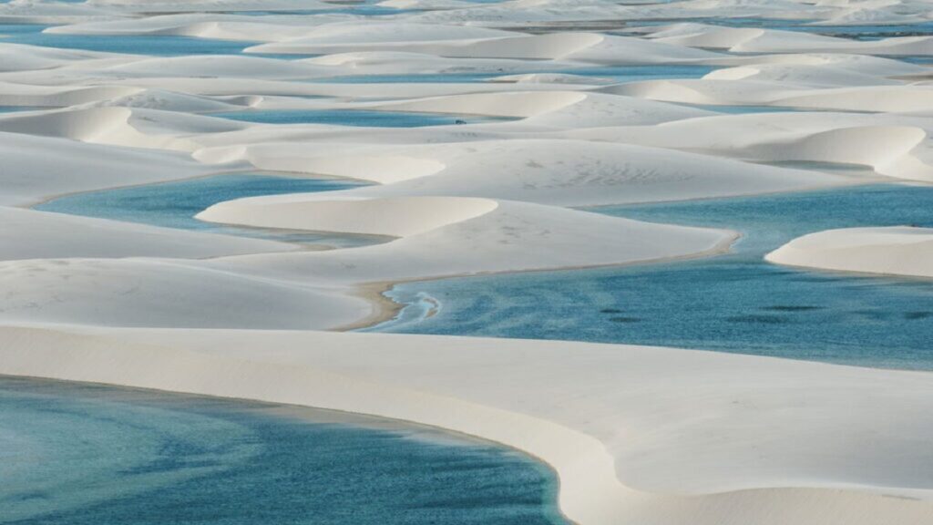 Lagoas sazonais de águas cristalinas formadas entre as dunas brancas dos Lençóis Maranhenses sob céu azul