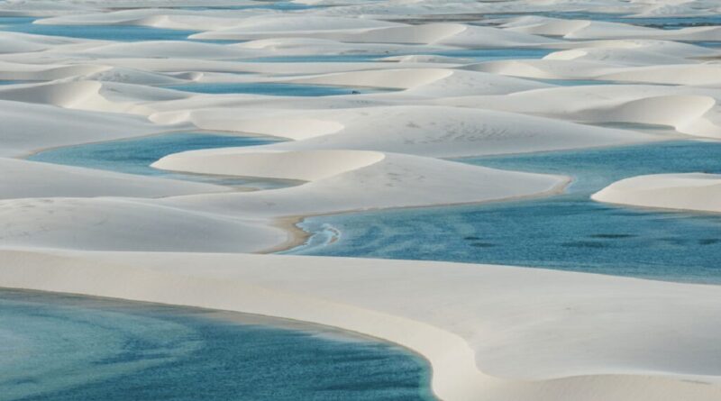 Lagoas sazonais de águas cristalinas formadas entre as dunas brancas dos Lençóis Maranhenses sob céu azul